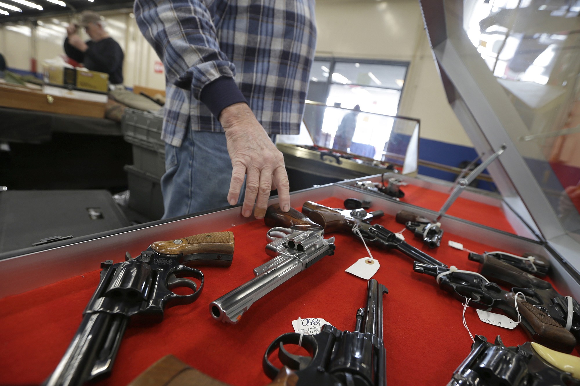 A dealer arranges handguns in a display case in advance of a show last month at the Arkansas State Fairgrounds in Little Rock, Ark. A major U.S.