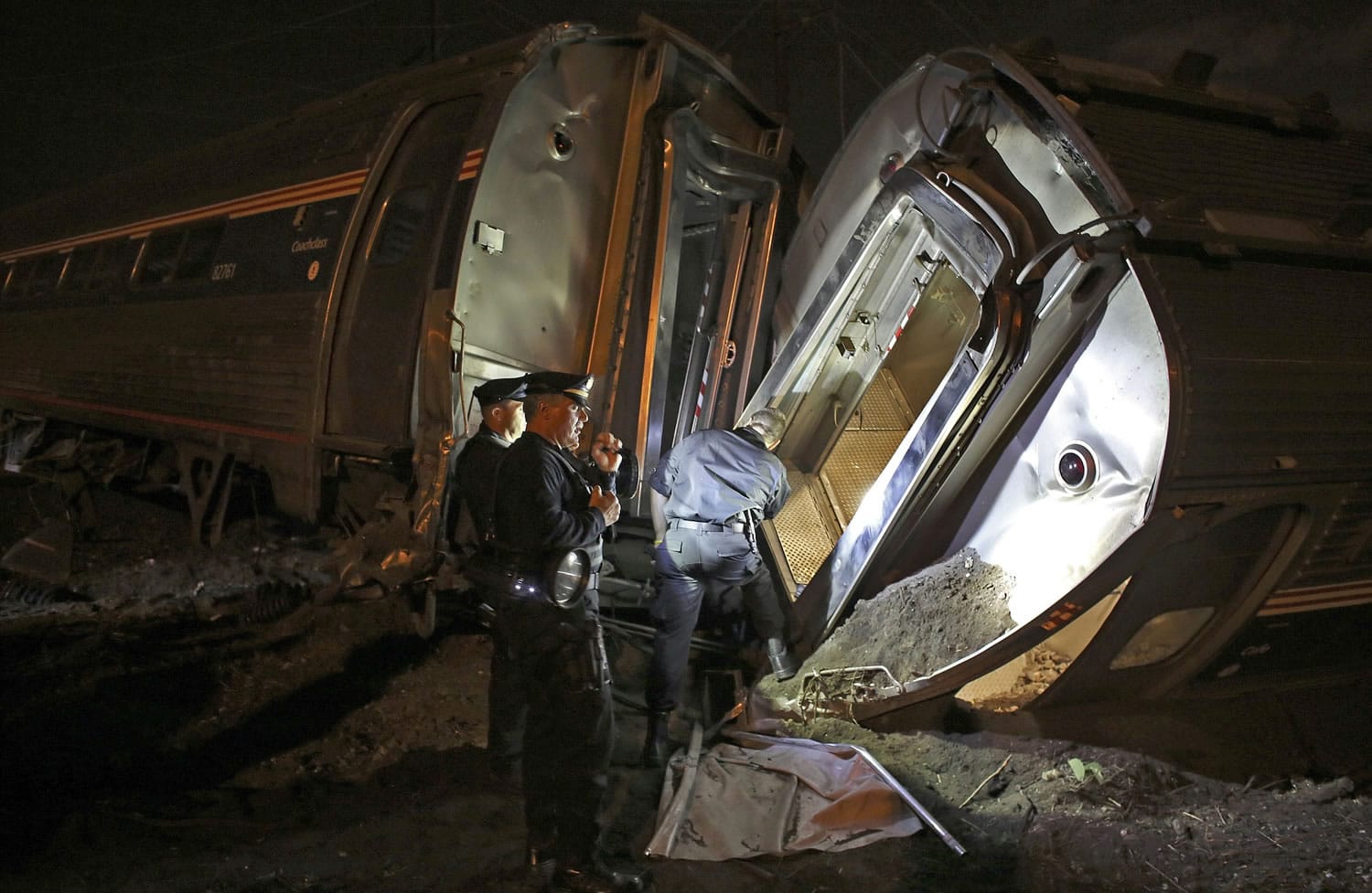 FILE - In this May 12, 2015 file photo, emergency personnel work the scene of a train wreck An Amtrak train headed to New York City derailed and crashed in Philadelphia. Amtrak says it will install video cameras inside locomotive cabs that record the actions of train engineers. The move follows a deadly derailment earlier this month in which investigators are searching for clues to the train engineer's actions just before the crash.