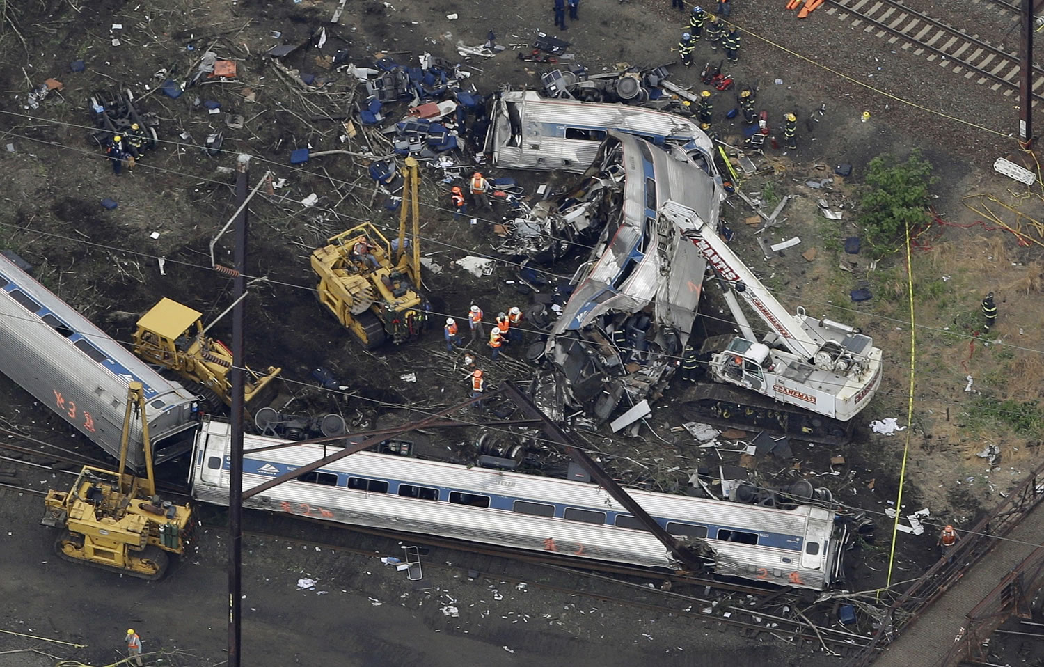 FILE - In this May 13, 2015, file photo, emergency personnel work at the scene of a deadly train wreck in Philadelphia. Federal safety regulators and Amtrak officials face questions at a congressional hearing Tuesday, June 2, 2015, on why technology to slow trains that are going too fast wasn?t in place before last month?s deadly derailment.