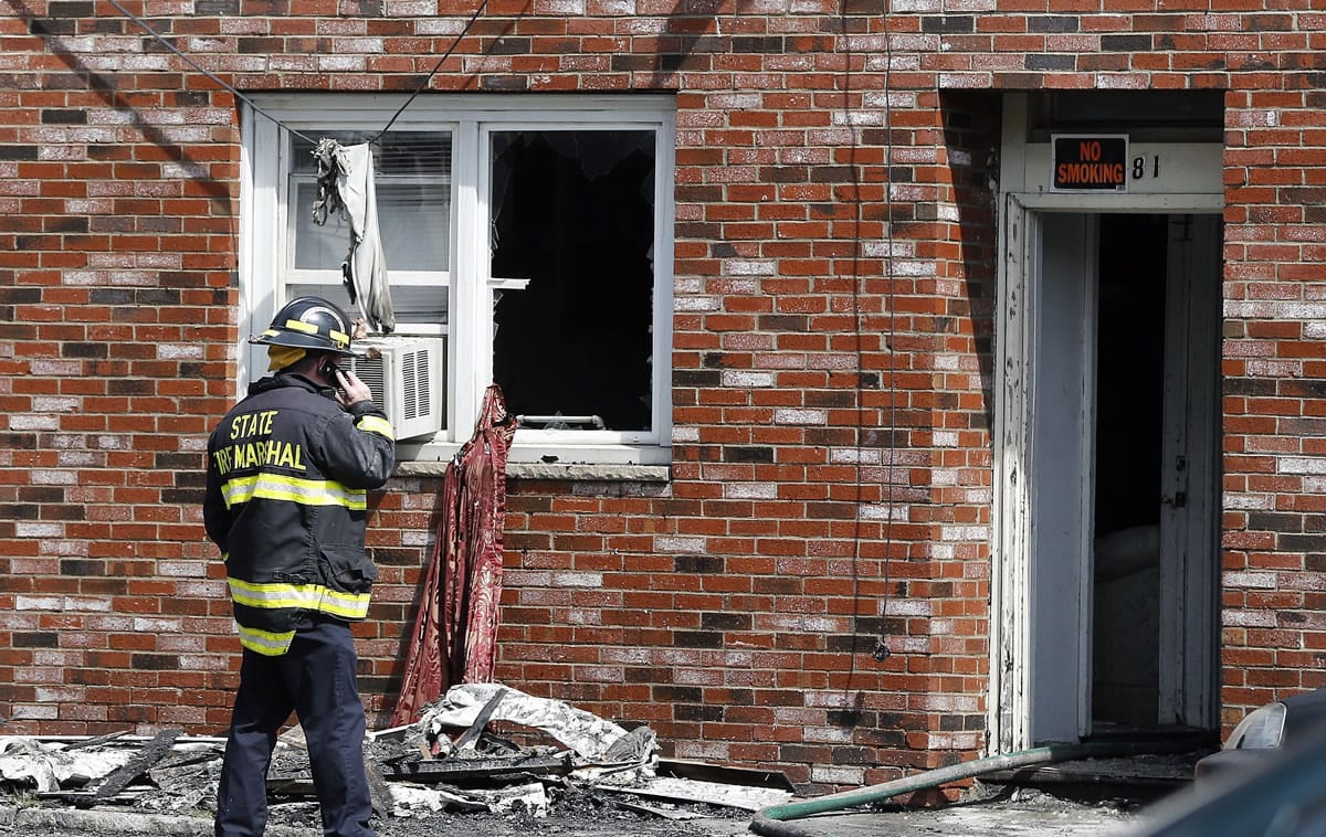 A state fire marshal talks on a cellphone at the scene of a burned three-story apartment and business building in Lowell, Mass., on Thursday.