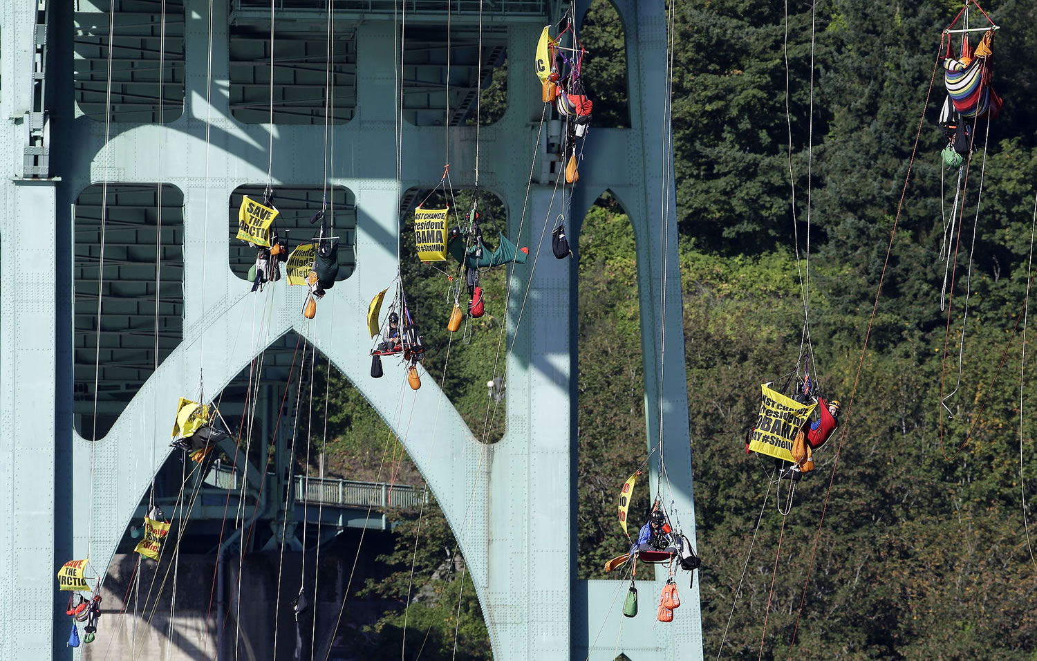 Activists hang from the St. Johns Bridge, Wednesday, July 29, 2015, in Portland, Ore., to protest the departure of Royal Dutch Shell PLC icebreaker Fennica, which is in Portland for repairs. The icebreaker is a vital part of Shell's exploration and spill-response plan off Alaska's northwest coast. Greenpeace officials say the activists have enough water and food to last for days, and can hoist themselves to allow other marine traffic to pass.