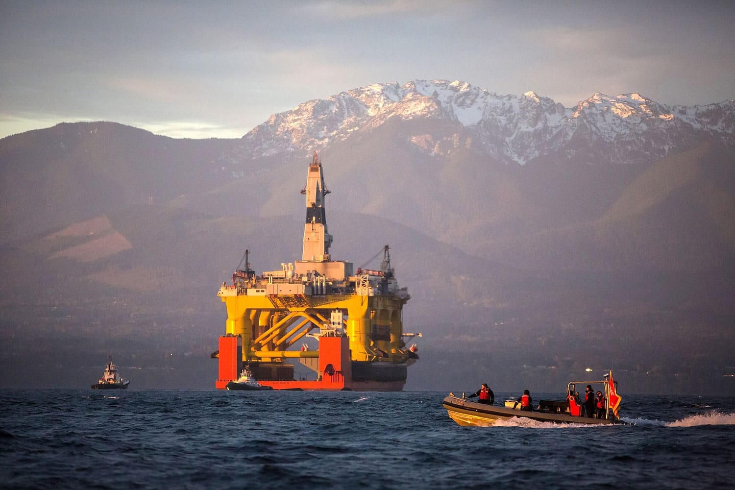 FILE - In this April 17, 2015 file photo, with the Olympic Mountains in the background, a small boat crosses in front of the Transocean Polar Pioneer, a semi-submersible drilling unit that Royal Dutch Shell leases from Transocean Ltd., as it arrives in Port Angeles, Wash., aboard a transport ship after traveling across the Pacific before its eventual Arctic destination. The U.S. government on Monday gave Shell the final permit it needs to drill for oil in the Arctic Ocean off Alaska's northwest coast for the first time in more than two decades.