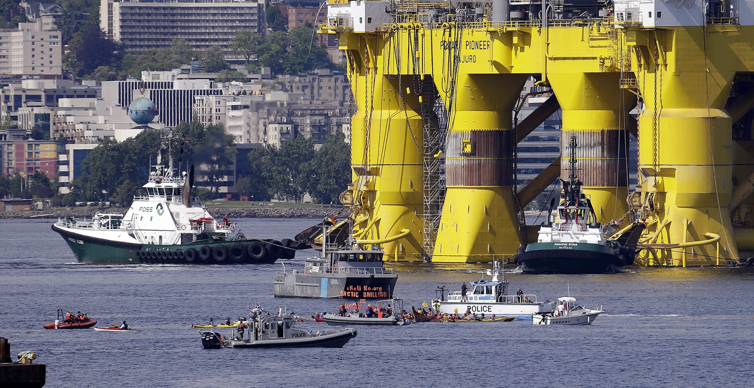 A small flotilla of kayakers and other protest boats follow as the oil drilling rig Polar Pioneer is towed toward a dock Thursday, May 14, 2015, in Elliott Bay in Seattle. The rig is the first of two drilling rigs Royal Dutch Shell is outfitting for oil exploration and was towed to the Port of Seattle site despite the city's warning that it lacks permits and threats by kayaking environmentalists to paddle out in protest.