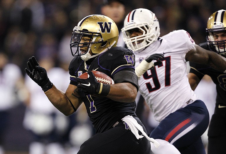 Washington's Chris Polk, left, is chased by Arizona's Mohammed Usman during the first half Saturday.