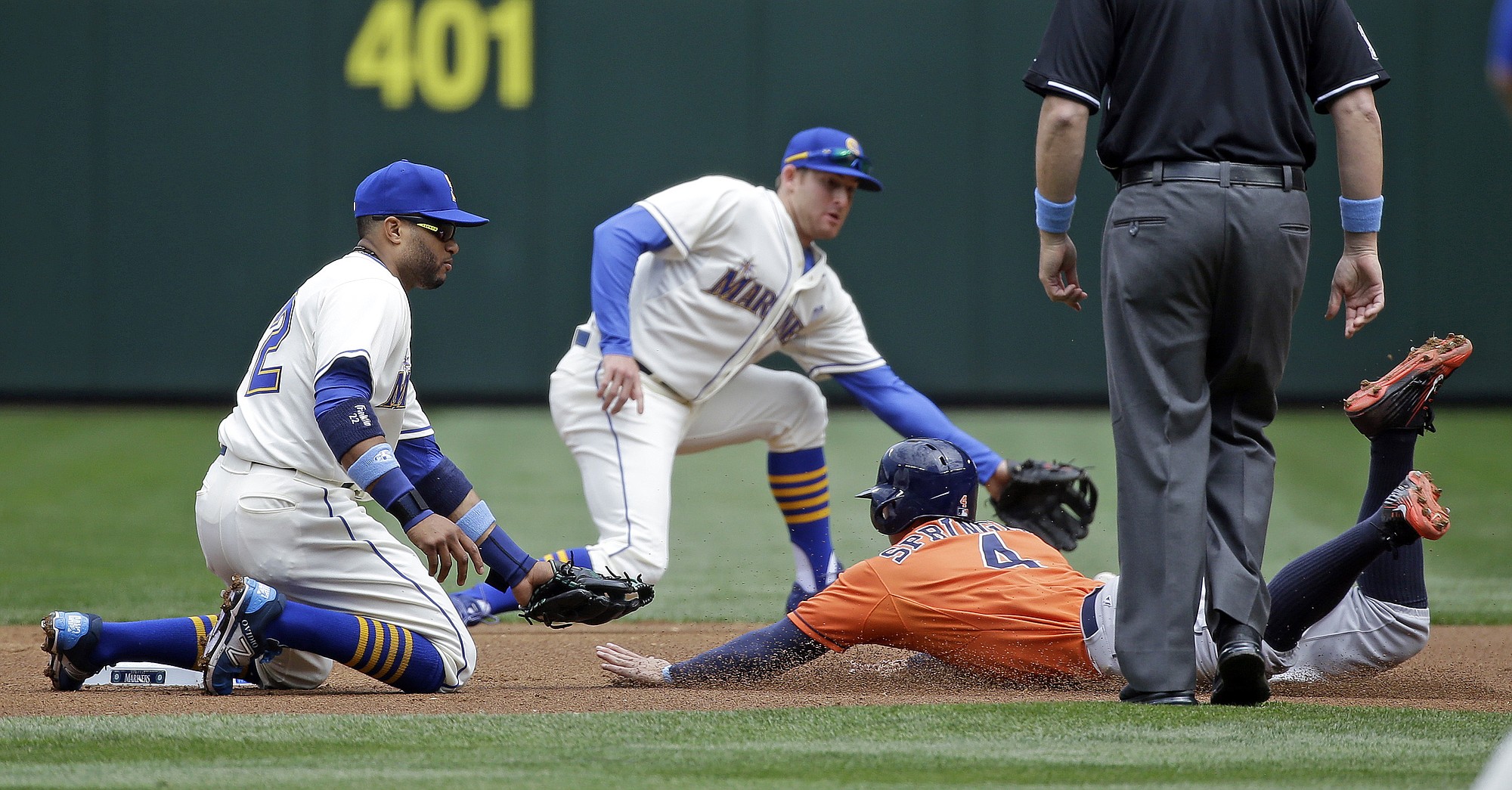 Houston Astros' George Springer (4) slides safely into second base as the ball gets past both Seattle Mariners second baseman Robinson Cano, left, and shortstop Brad Miller in the first inning Sunday, June 21, 2015, in Seattle. Springer advanced on a wild pitch.
