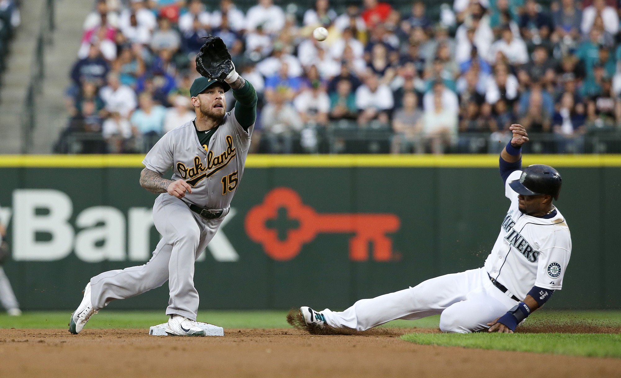 Oakland Athletics third baseman Brett Lawrie reaches to catch the pick-off throw as Seattle Mariners' Robinson Cano, right, attempts to steal second base in the second inning Monday, Aug. 24, 2015, in Seattle. Lawrie's tag on Cano was ruled an out after the initial safe call on the field was challenged by the Athletics. (AP Photo/Ted S.