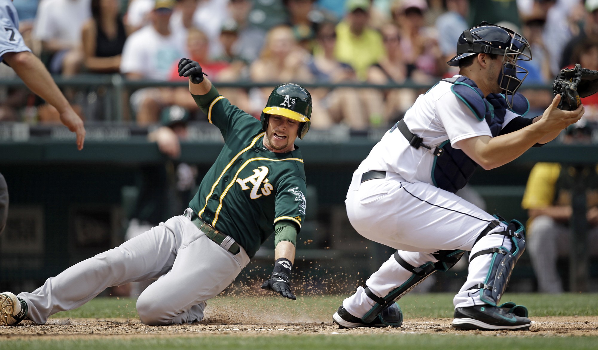 Oakland Athletics' Jed Lowrie, left, scores as Seattle Mariners catcher Mike Zunino waits for the ball in the fifth inning of a baseball game Sunday, July 13, 2014, in Seattle.
