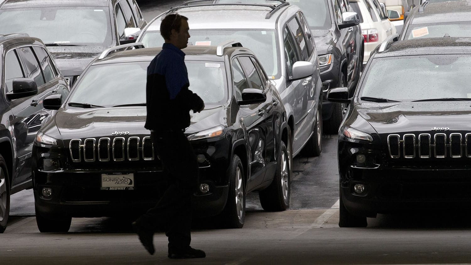 A worker on a Chrysler car lot passes lines of mostly Jeep SUVs on Tuesday in San Diego.