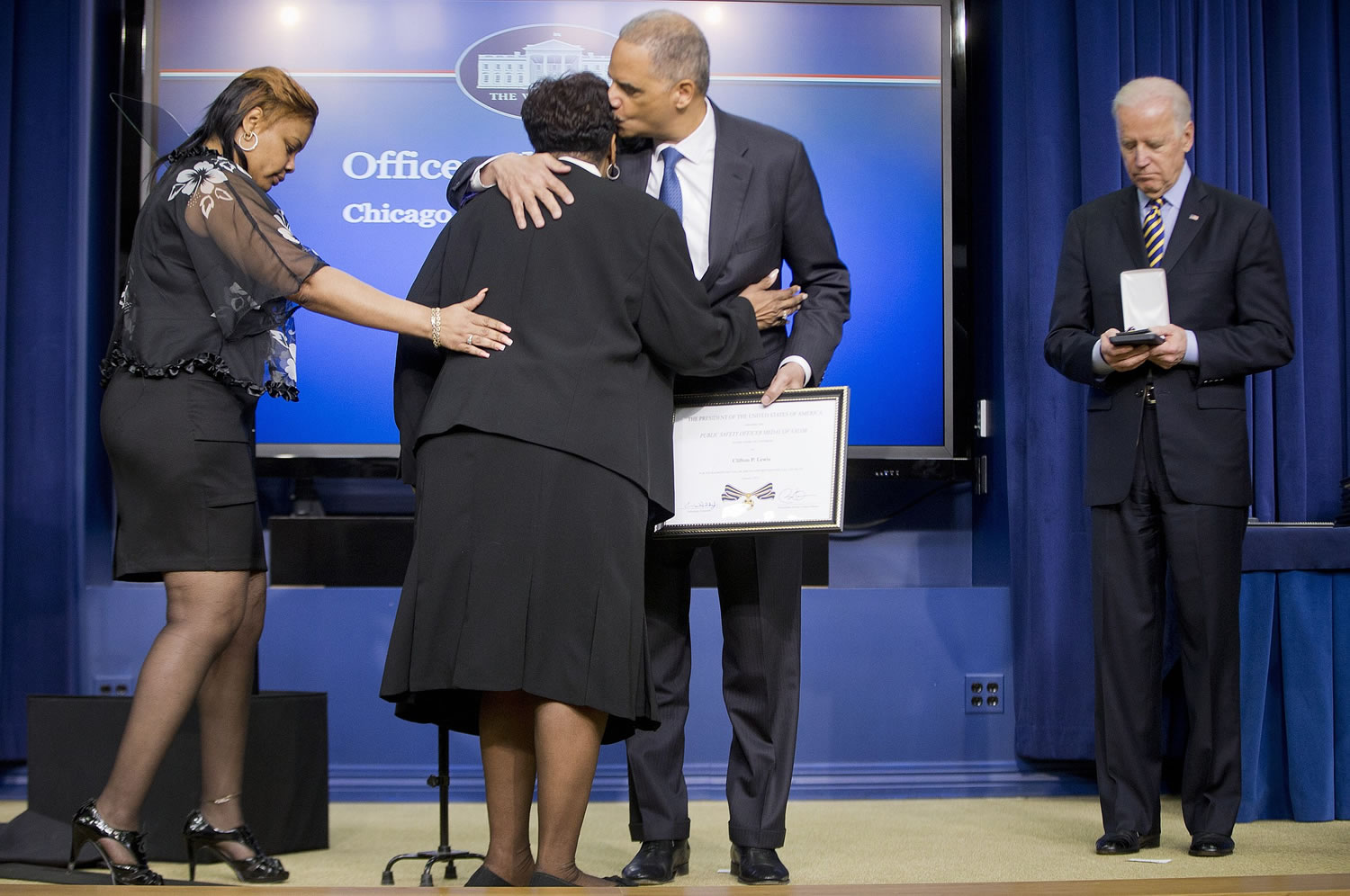 Attorney General Eric Holder embraces Maxine Hooks, center, mother of late Chicago Police Officer Clifton Lewis, who was awarded the Medal of Valor posthumously during a ceremony Wednesday in the Old Executive Office Building on the White House Complex in Washington.