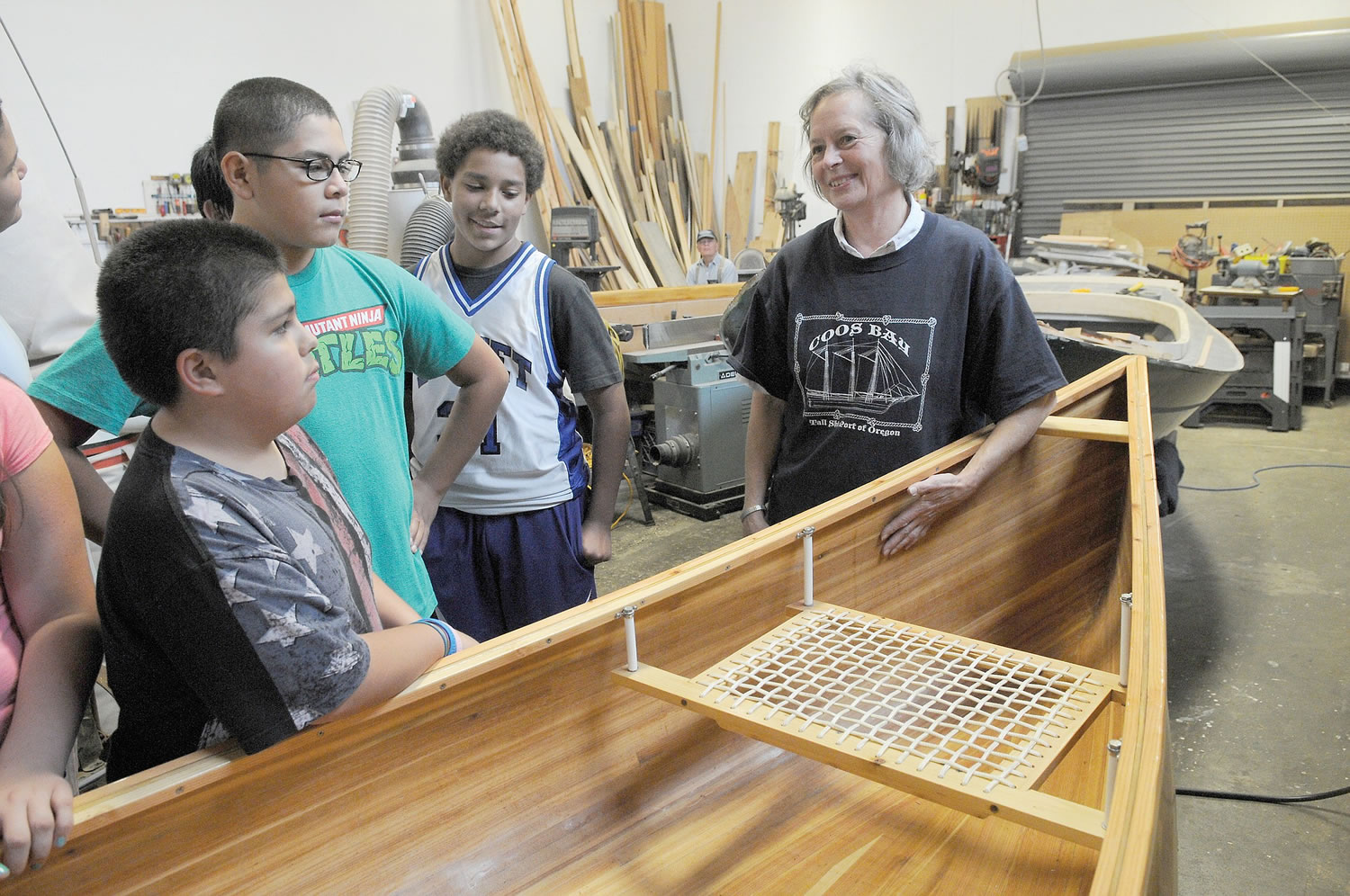 Sarah Reckon, a volunteer at the Coos Bay Boat Building Center in Coos Bay, Ore., takes seventh-graders from Sunset Middle School on a facilities tour on Nov. 6. The school is pairing with the center for a boat-building project.