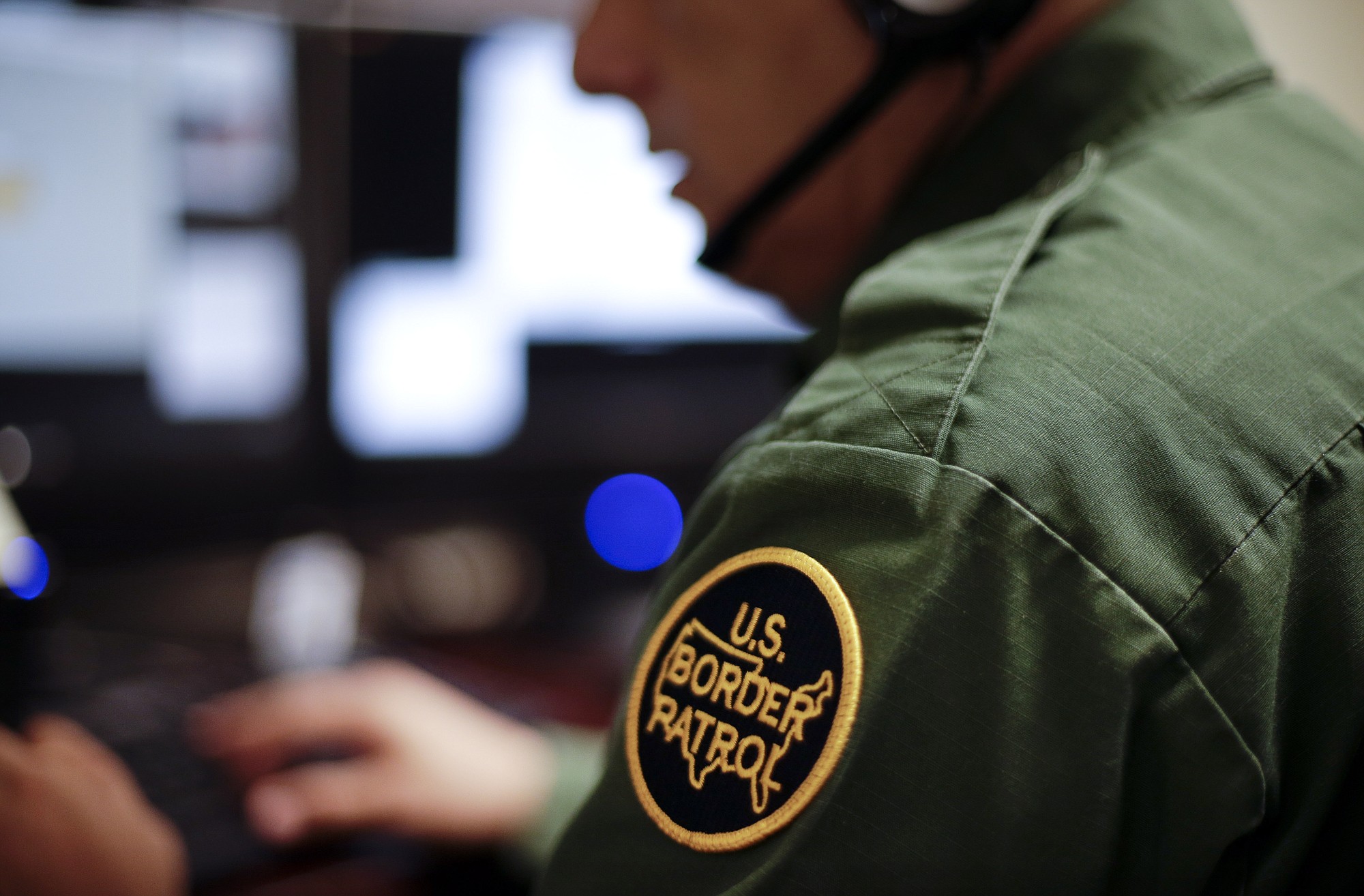 A Border Patrol agent uses a headset and computer June 5 at a facility in San Diego to conduct a long-distance interview by video with a person arrested crossing the border in Texas.