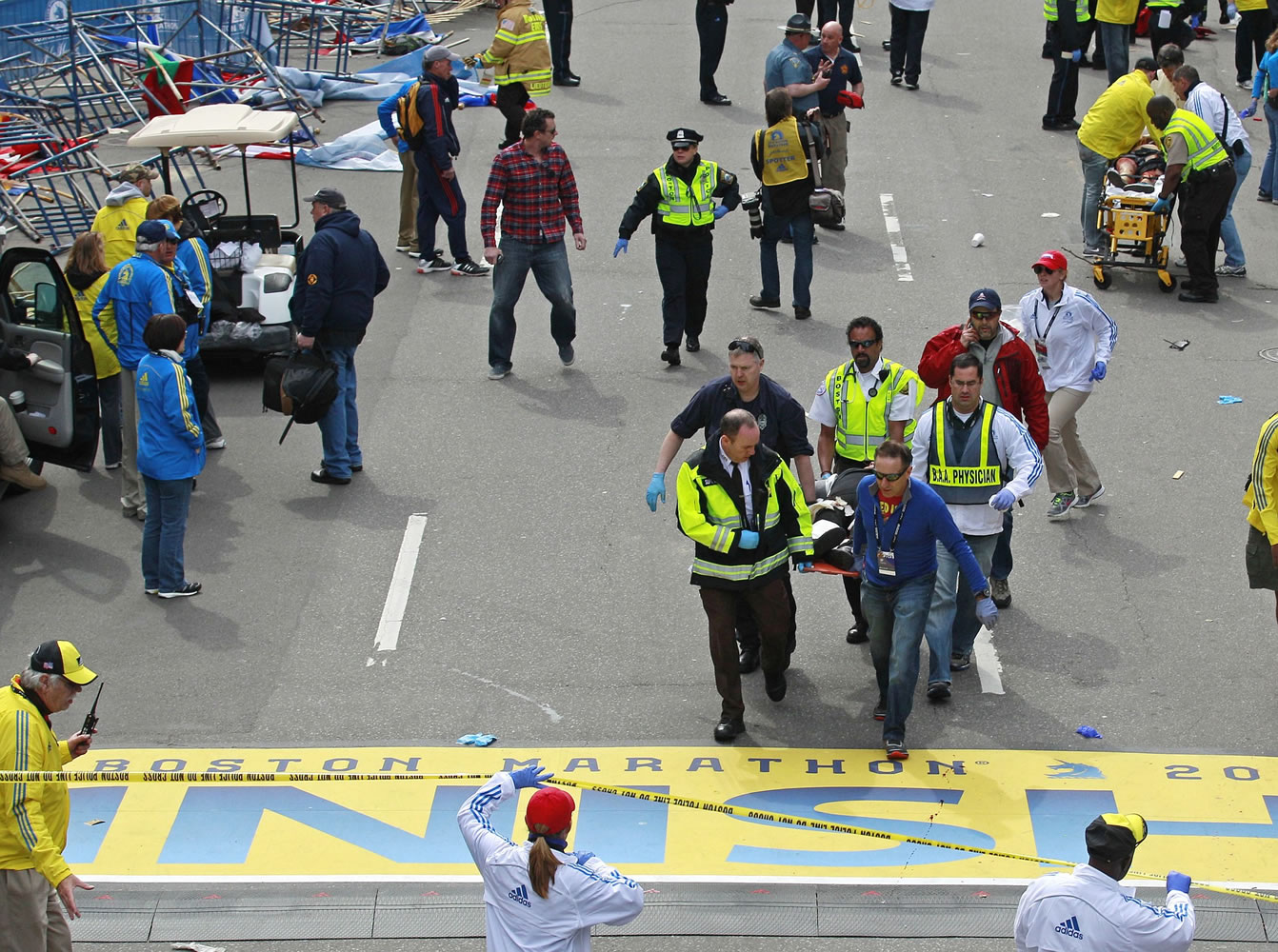 Medical workers wheel the injured across the finish line during the 2013 Boston Marathon following an explosion in Boston on Monday.