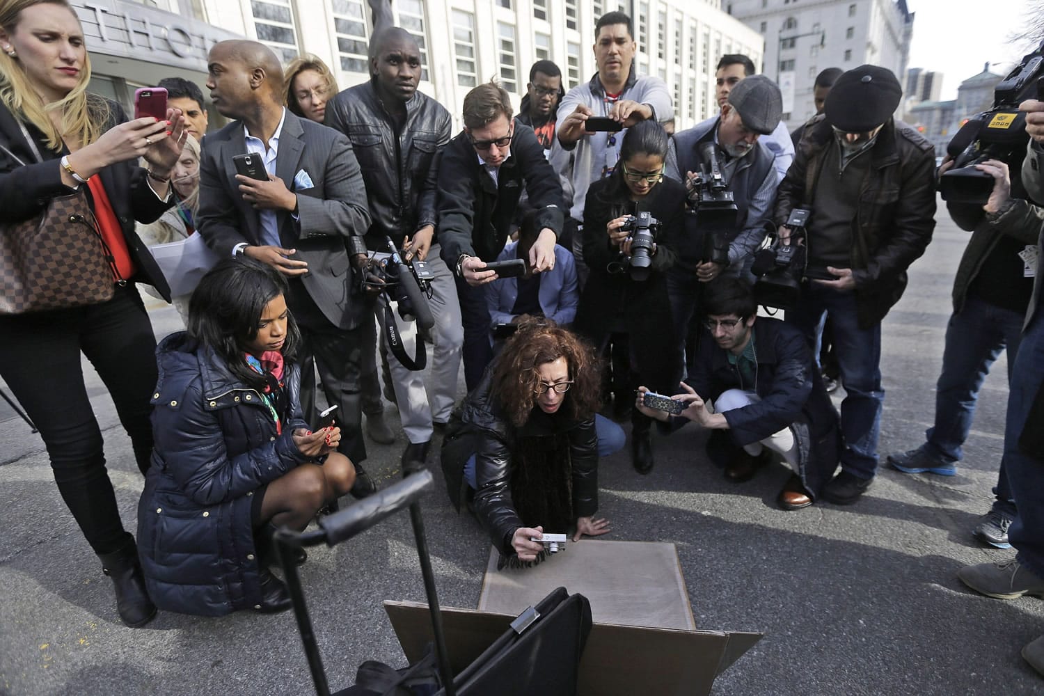 Members of the media surround court artist Jane Rosenberg, center, to copy her artwork of terrorist suspects outside Federal court in the Brooklyn borough of New York. Rosenberg has taken some criticism for her Aug.