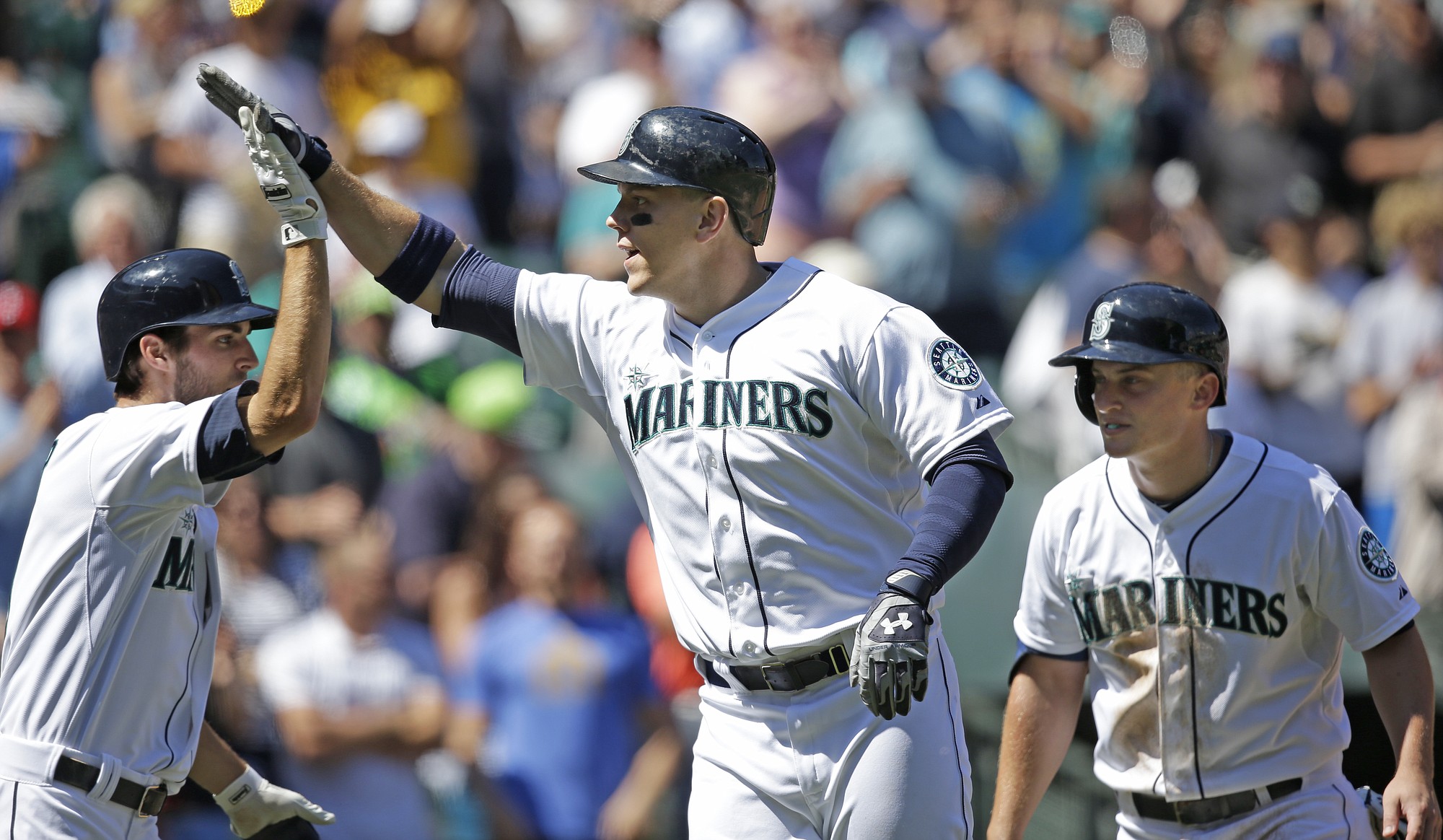 Seattle Mariners' Logan Morrison, center, is congratulated by Chris Taylor, left, and followed by Kyle Seager on Morrison's three-run home run against the Atlanta Braves in the third inning of a baseball game Wednesday, Aug. 6, 2014, in Seattle.