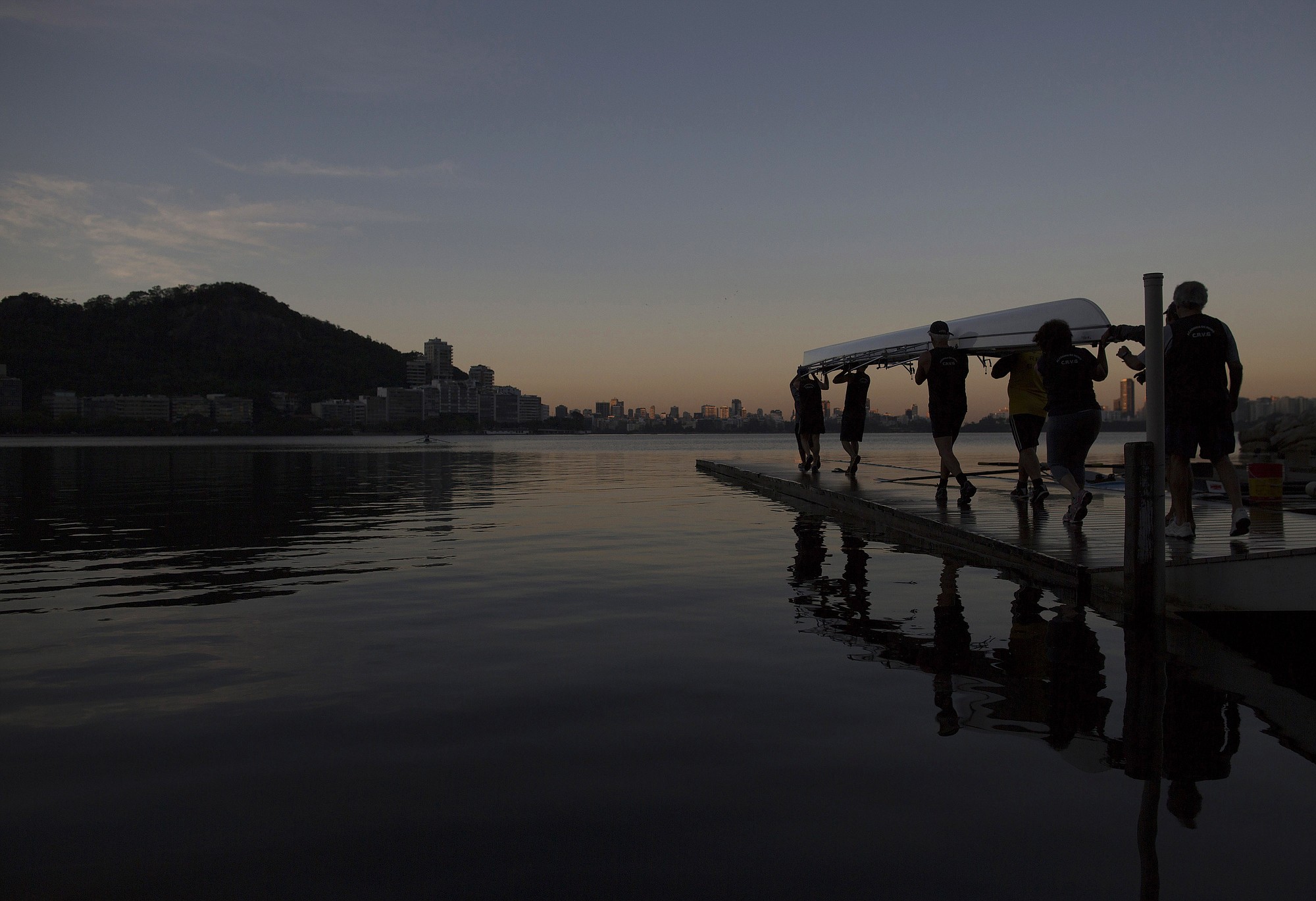 Men carry a rowing boat for a practice session in the Rodrigo de Freitas Lake, in Rio de Janeiro, Brazil.