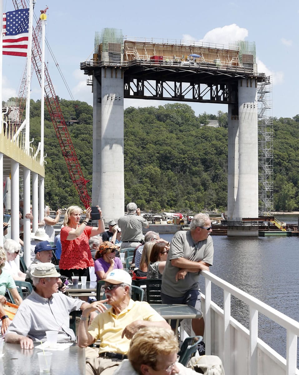 A pier with Wisconsin in the background towers over the St. Croix River as people pack the top deck of a river boat on a guided tour last month to view construction of the mile-long St. Croix Crossing bridge linking Minnesota and Wisconsin near Stillwater, Minn.