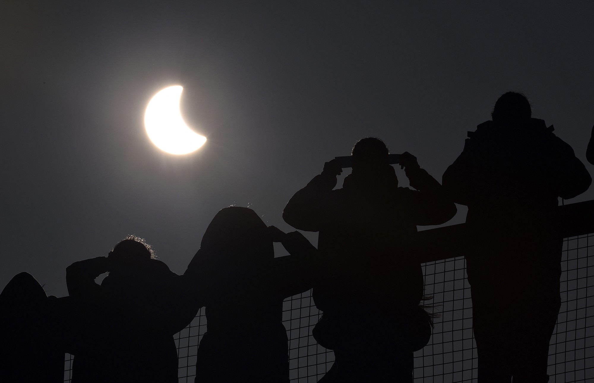 People watch as a solar eclipse begins over the Eden Project near St.