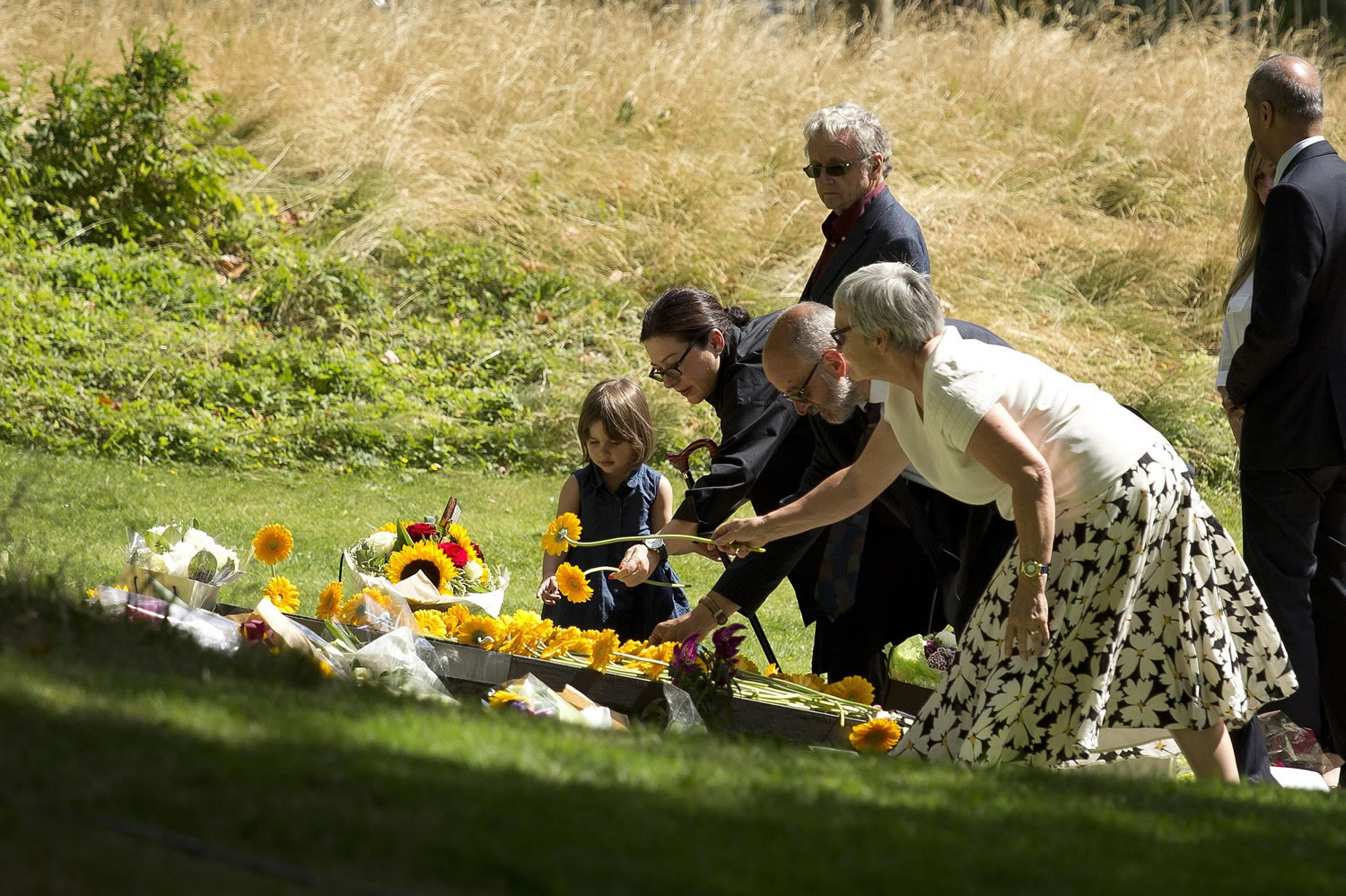 Australia's Gill Hicks, second from left, who lost both her legs in the July 7, 2005, terrorist attacks on London's transit system, lays a flower flanked by her daughter Amelie, left, during a service Tuesday for survivors and relatives of the victims to mark the 10-year anniversary of the 7/7 London attacks, at the 7/7 memorial in Hyde Park, London. Britons paused in silence and walked in solidarity to mark the anniversary. Four British men inspired by al-Qaida blew themselves up on three London subway trains and a bus during the morning rush hour on July 7, 2005, killing 52 commuters and injuring more than 700.