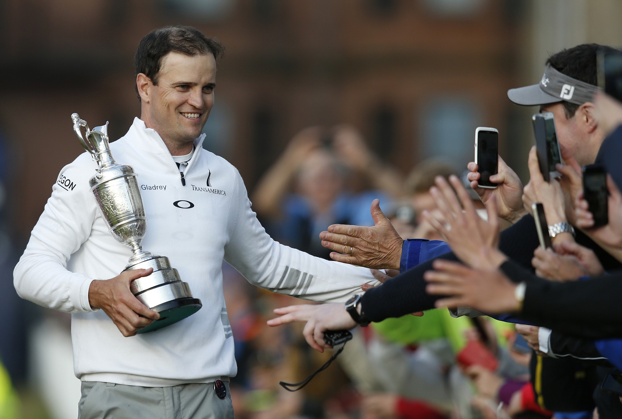 United States' Zach Johnson celebrates with members of the public as he holds the Claret Jug trophy after winning a playoff after the final round at the British Open Golf Championship at the Old Course, St. Andrews, Scotland, on Monday, July 20, 2015.