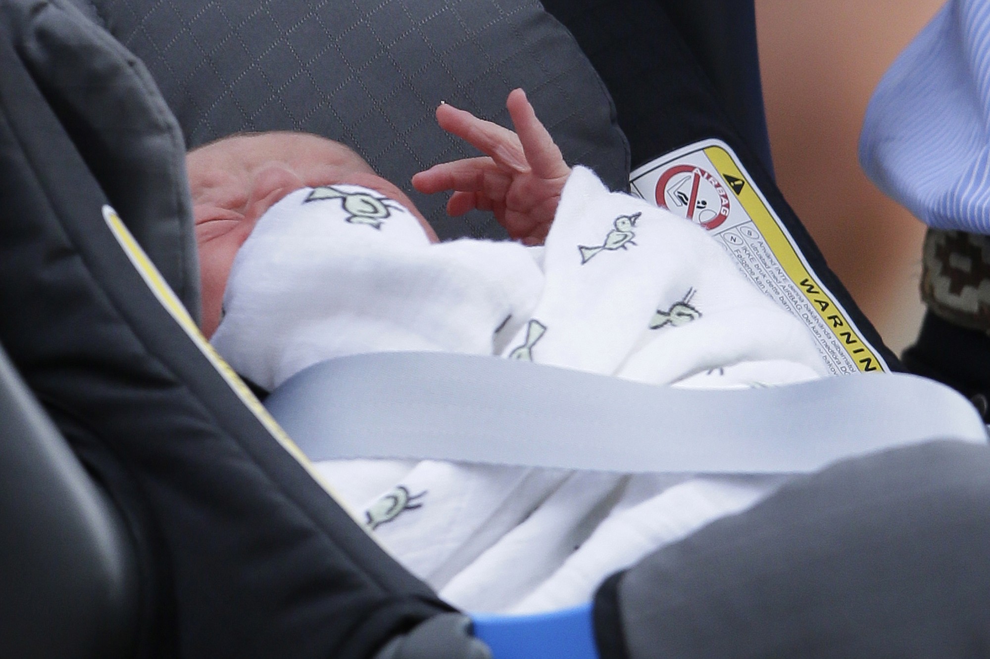 The Prince of Cambridge lays in a carseat as his parents, Britain's Prince William and Kate, Duchess of Cambridge, leave St.