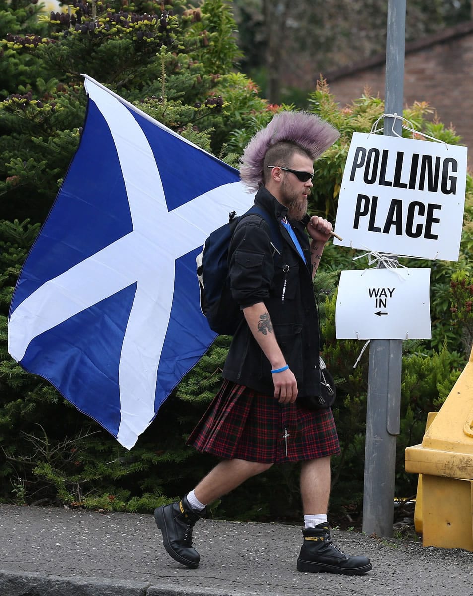 Chris McAleese holds a Saltire flag as he walks past Bannockburn Polling Station in Scotland on Thursday.