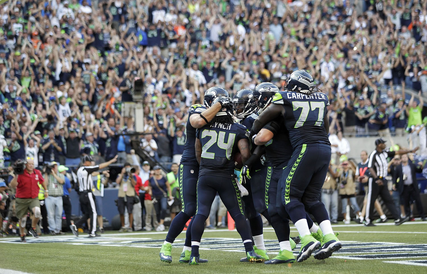 Fans cheer as Seattle Seahawks running back Marshawn Lynch (24) celebrates with teammates after Lynch scored the game-winning touchdown in overtime of an NFL football game against the Denver Broncos, Sunday, Sept. 21, 2014, in Seattle. The Seahawks won 26-20.