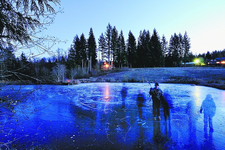 Six children play on a frozen pond north of Battle Ground on Tuesday evening in this long-exposure photograph, which gives the children who were moving a ghostly appearance.