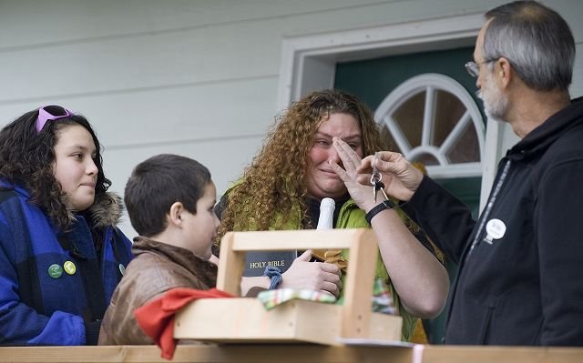 Kelly Coleman, center, with her children, Dakota, 13, left, and Brody, 9, is overcome with emotion as Russ Chambers presents her with the keys to the family's new home.