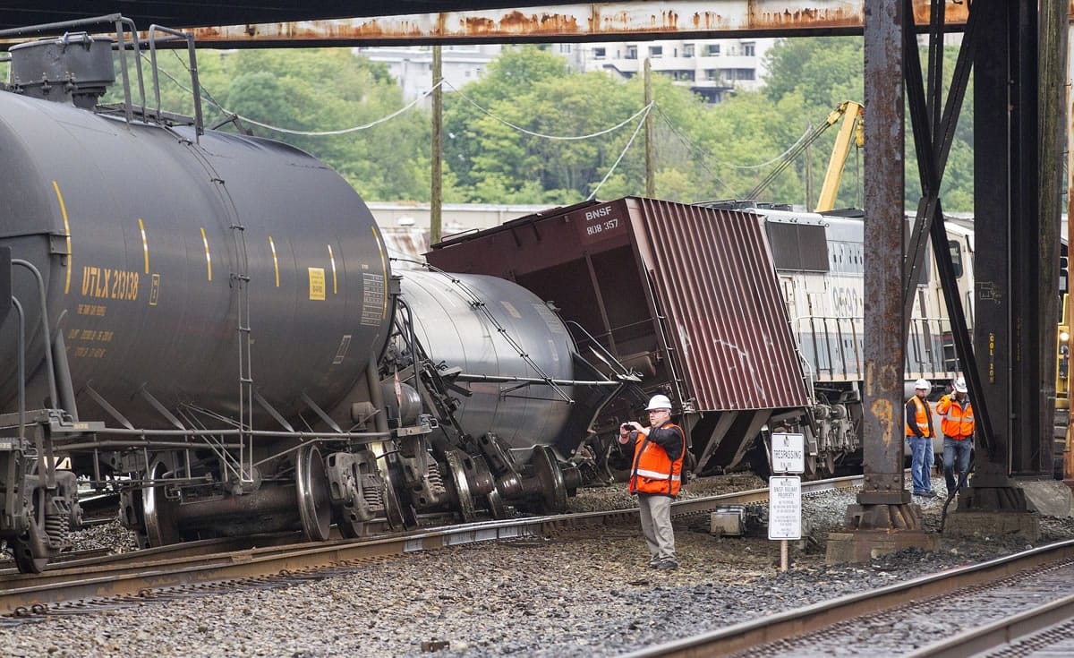 An investigator photographs the scene where a locomotive and cars carrying crude oil went off the track beneath the Magnolia Bridge in the Interbay neighborhood of Seattle on Thursday morning.