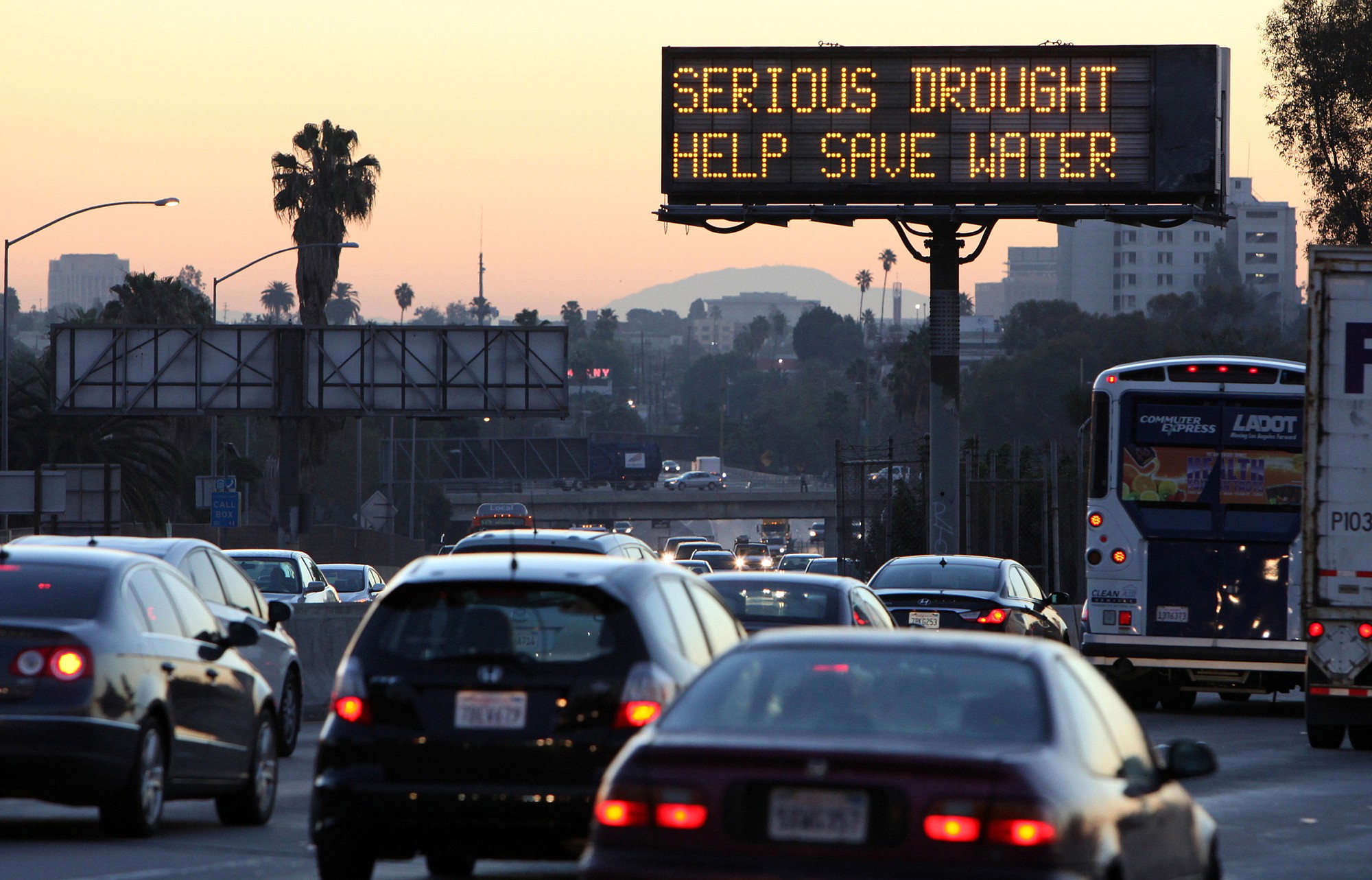 Morning traffic makes its way toward downtown Los Angeles along the Hollywood Freeway past an electronic sign warning of severe drought.