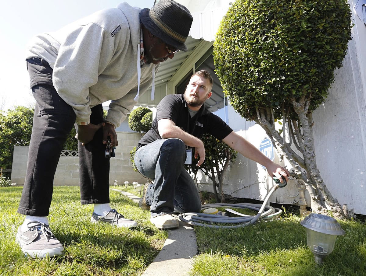 Associated Press files
Steve Upton, right, demonstrates how to use the water timer he installed on a water spigot at the home of Larry Barber in March 2014 in Sacramento, Calif.