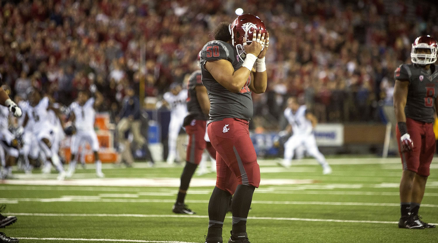 Washington State special teams blocker Lyman Faoliu (50) covers his face after while California players celebrate in the background after kicker Quentin Breshears missed a potential game-winning field goal with 15 seconds left Saturday, Oct. 4, 2014, at Martin Stadium in Pullman. California won 60-59.