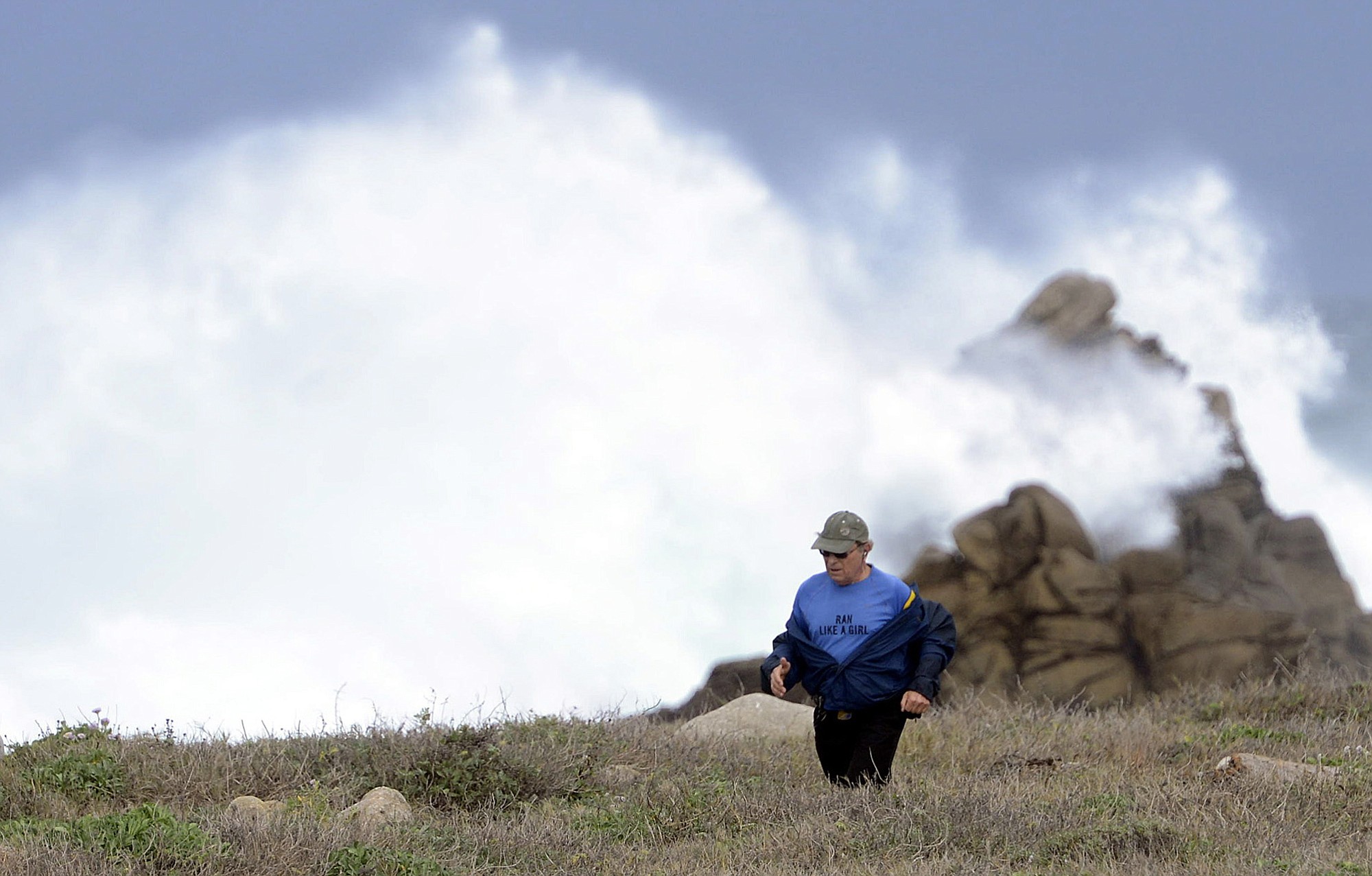 Peter Krasa runs into heavy winds and past large waves breaking along the shore between Point Joe and Bird Rock in Pebble Beach, Calif., as a storm blows in on Friday.