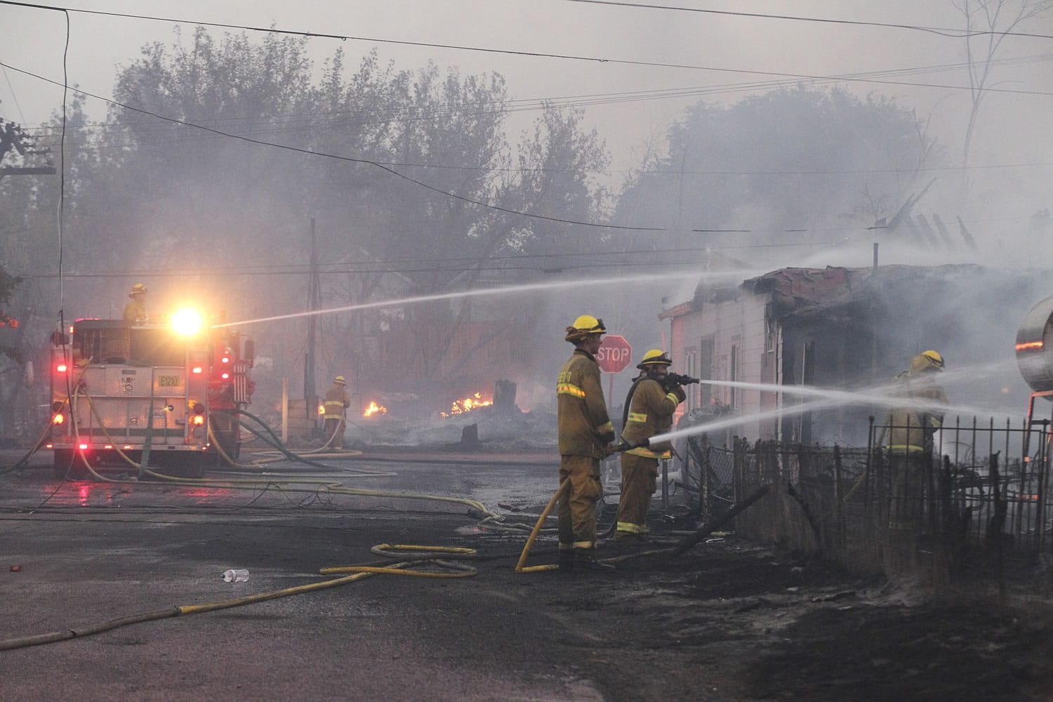 Firefighters work to put out fires and protect structures along Center Street on Monday in Weed, Calif.