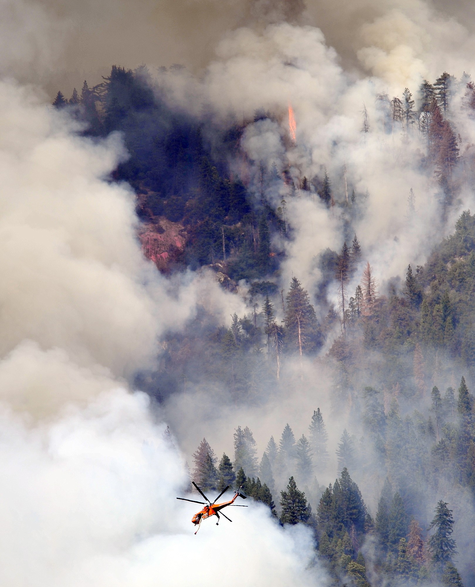 A helicopter flies over Willow Creek Canyon as a wildfire continues burning in the Sierra near Bass Lake, Calif., on Monday.