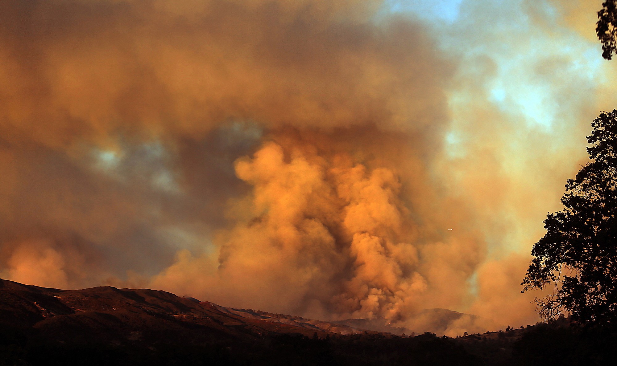 Smoke rises above the landscape as the Rocky Fire continues to burn at sunset Wednesday outside Lower Lake, Calif.