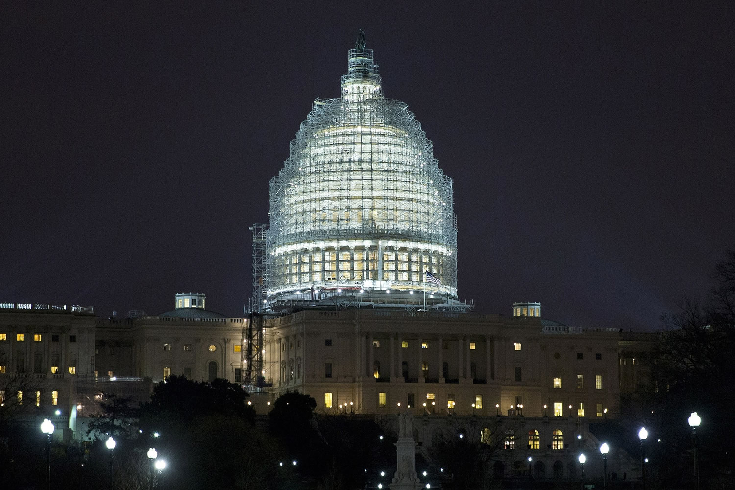 Lights illuminate the U.S. Capitol, which is covered in scaffolding for restoration, in Washington on Wednesday.