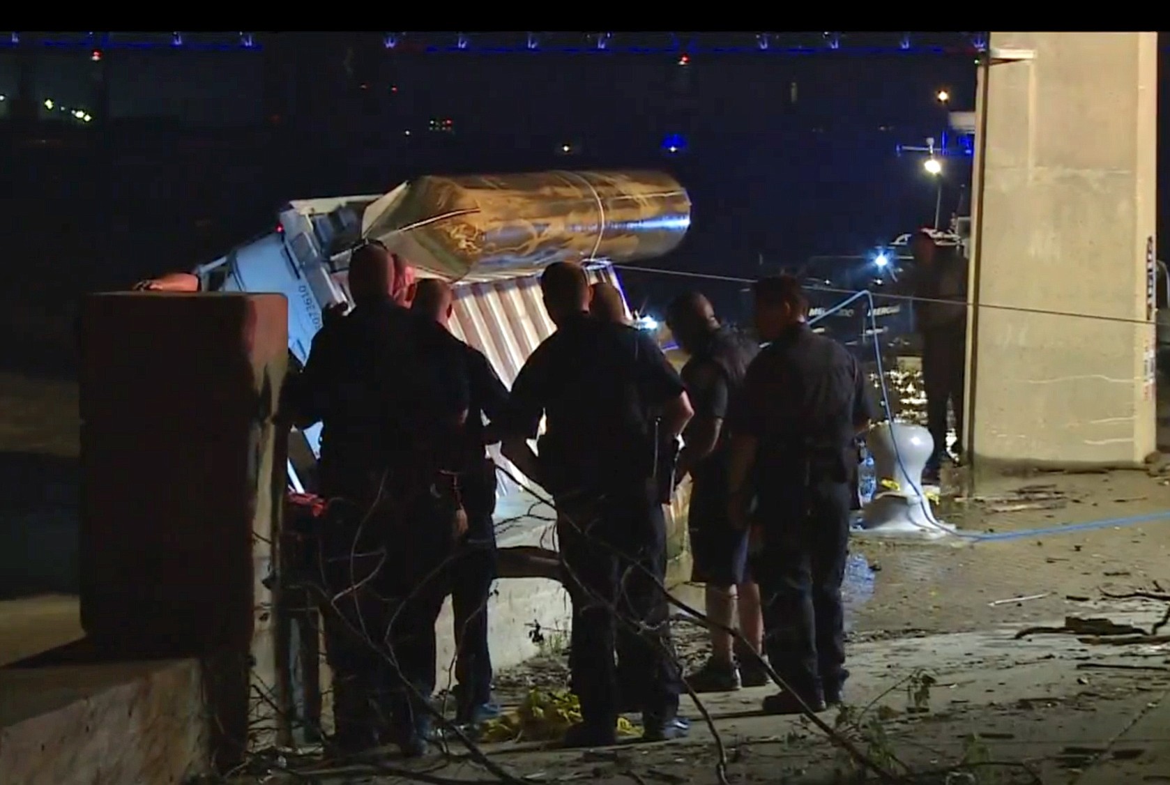 In this image taken from video, police officers look on as an overturned pontoon boat is pulled out of the water of the Ohio River on Saturday in Louisville, Ky.