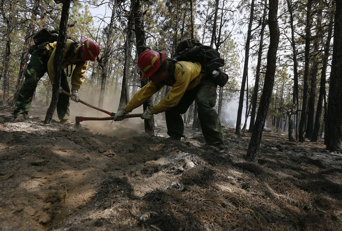 Firefighters Ron Huffman, left, and Ivan Harmon rake out hot spots Sunday in the scorched ground near an area that investigators were searching for the cause of the Two Bulls Fire west of Bend, Ore.