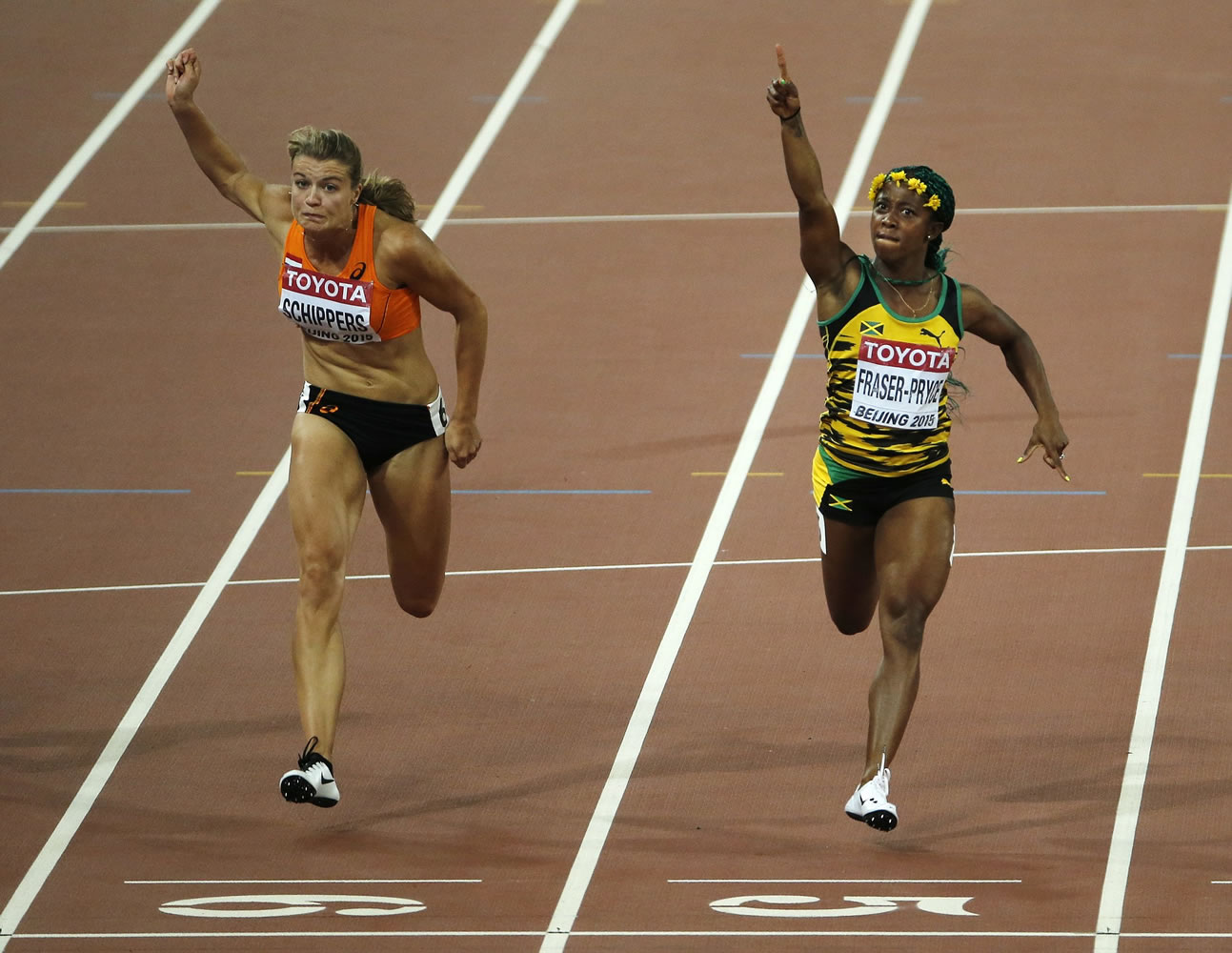 Jamaica's gold medal winner Shelly-Ann Fraser-Pryce, right, and silver medal winner Dafne Schippers of the Netherlands cross the line of the women's 100-meter final at the World Athletics Championships at the Bird's Nest stadium in Beijing, Monday, Aug.