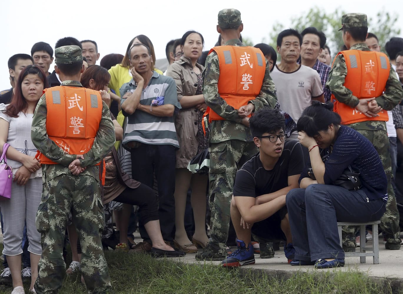 Chinatopix via AP
A woman, right, whose parents were onboard the capsized cruise ship, grieves along the Yangtze River on Wednesday near Jianli, China, as paramilitary policemen stand guard to prevent people from getting near rescue efforts.