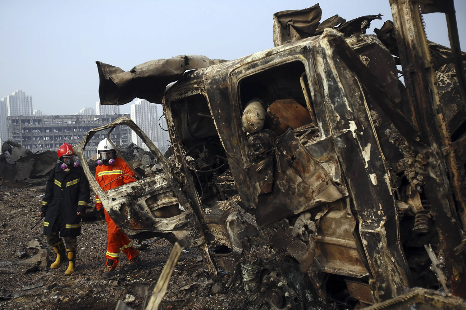 Firefighters walk past a destroyed fire truck at the site of an explosion in northeastern China's Tianjin municipality.