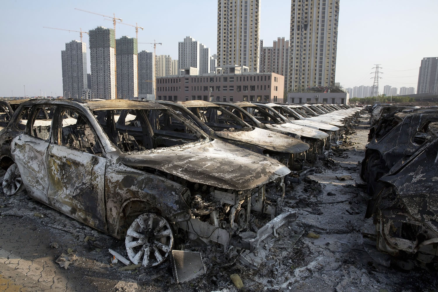 Charred remains of new cars are photographed after an explosion tore through the parking lot of a warehouse in northeastern China's Tianjin municipality, Thursday, Aug. 13, 2015.  Huge explosions in the warehouse district sent up massive fireballs that turned the night sky into day in the Chinese port city of Tianjin, officials and witnesses said Thursday.
