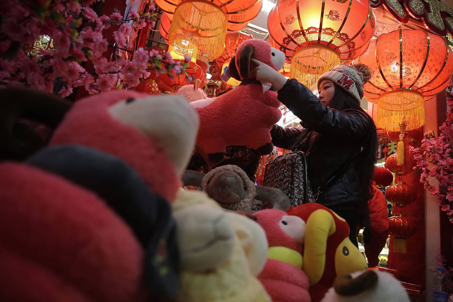 A woman shops toy sheep for Lunar New Year decorations in Beijing, China.
