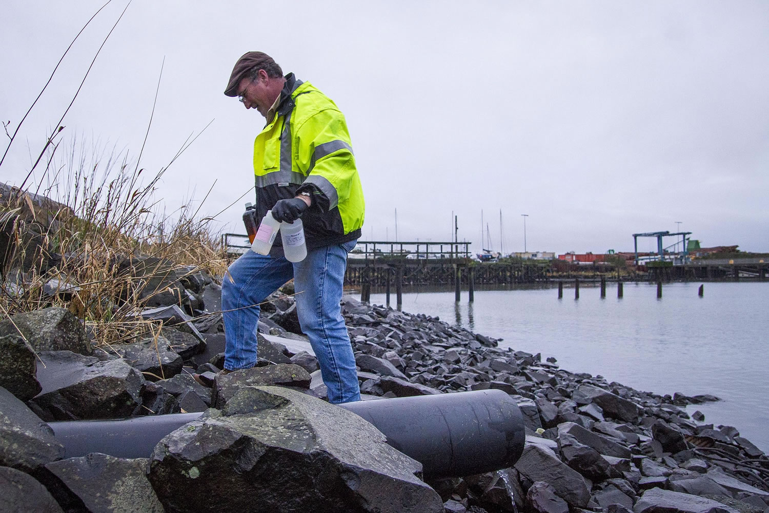Robert Evert, permit and project manager for the Port of Astoria, collects samples along Pier 2 in Astoria, Ore.