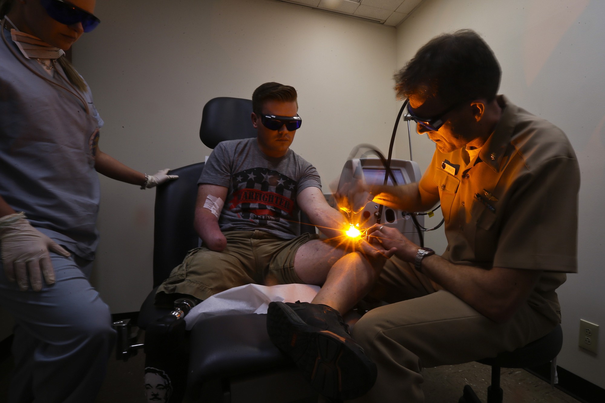 Retired Marine Gunnery Sgt. Brian Meyer, center, gets laser treatment from Navy Cmdr.