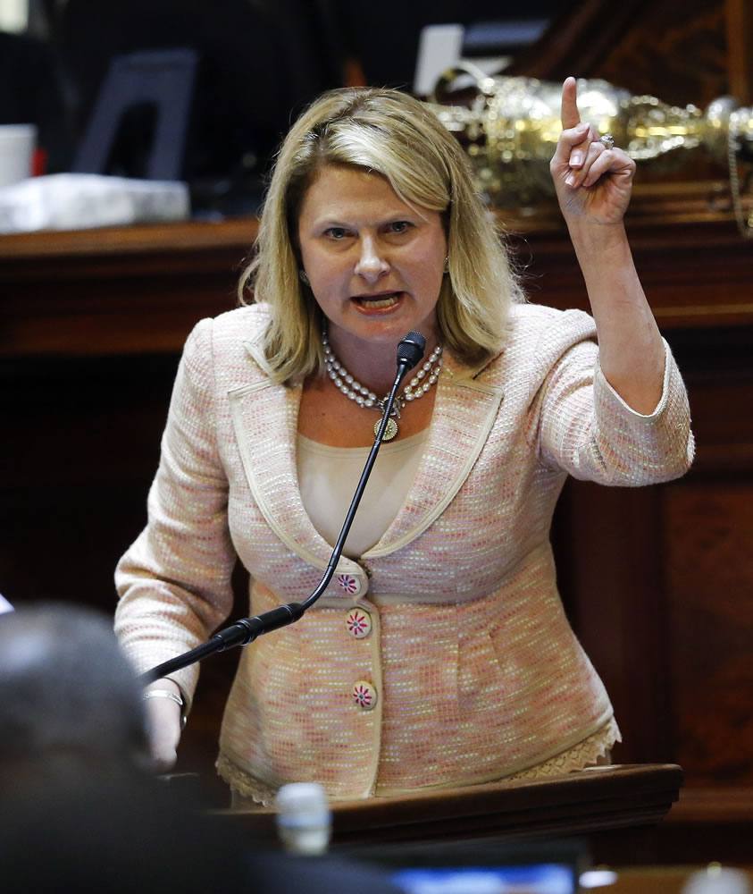 Photos by JOHN BAZEMORE/Associated Press
Rep. Jenny Horne, R-Summerville, gets emotional Wednesday as she speaks during debate over a bill calling for the Confederate flag to be removed from the Capitol grounds in Columbia, S.C.  At right, a Confederate battle flag flies next to a Civil War memorial outside the statehouse in Columbia.