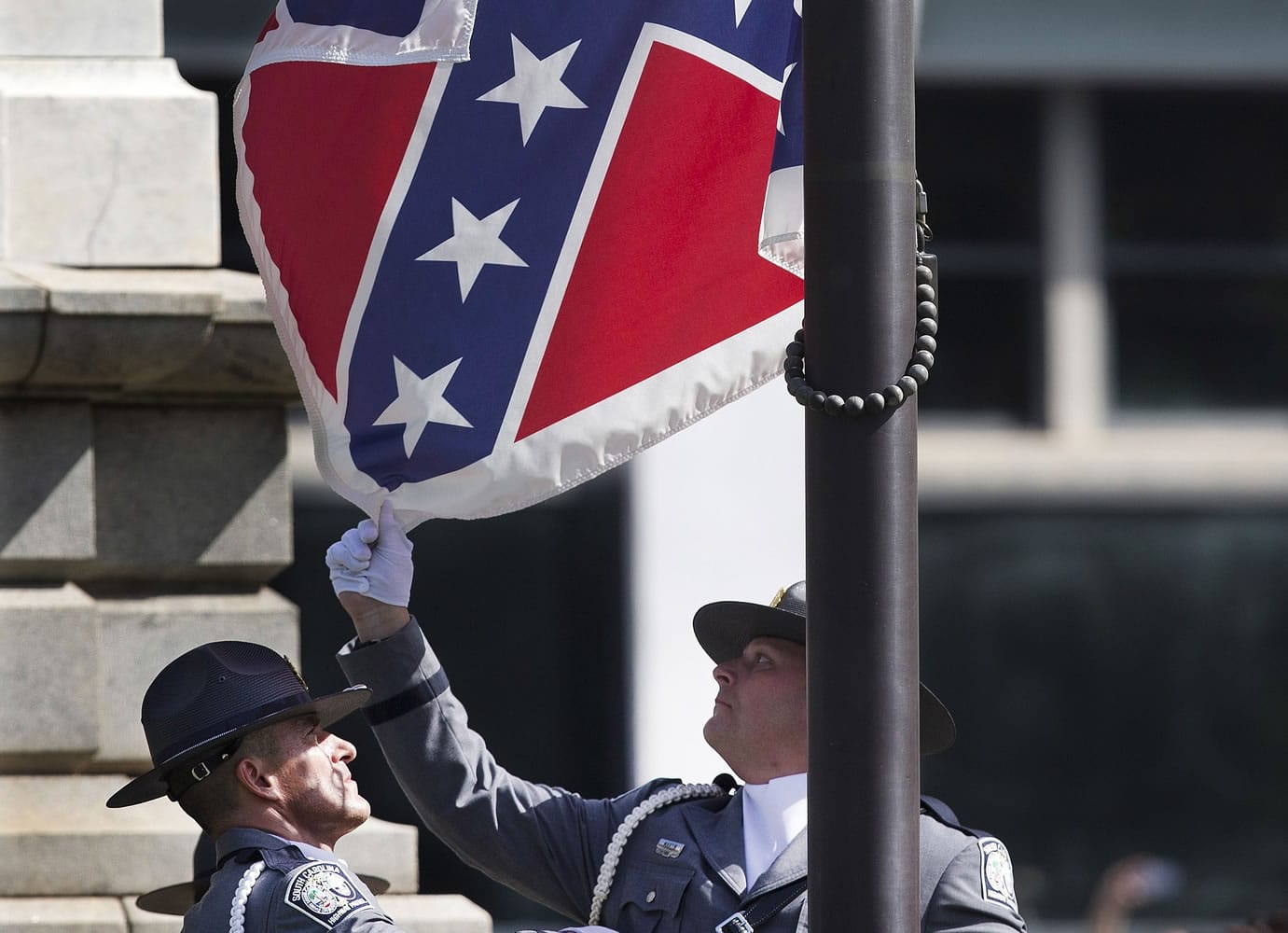An honor guard from the South Carolina Highway patrol lowers the Confederate battle flag as it is removed from the Capitol grounds Friday in Columbia, S.C. The Confederate flag was lowered from the grounds of the South Carolina Statehouse to the cheers of thousands on Friday, ending its 54-year presence there and marking a stunning political reversal in a state where many thought the rebel banner would fly indefinitely.