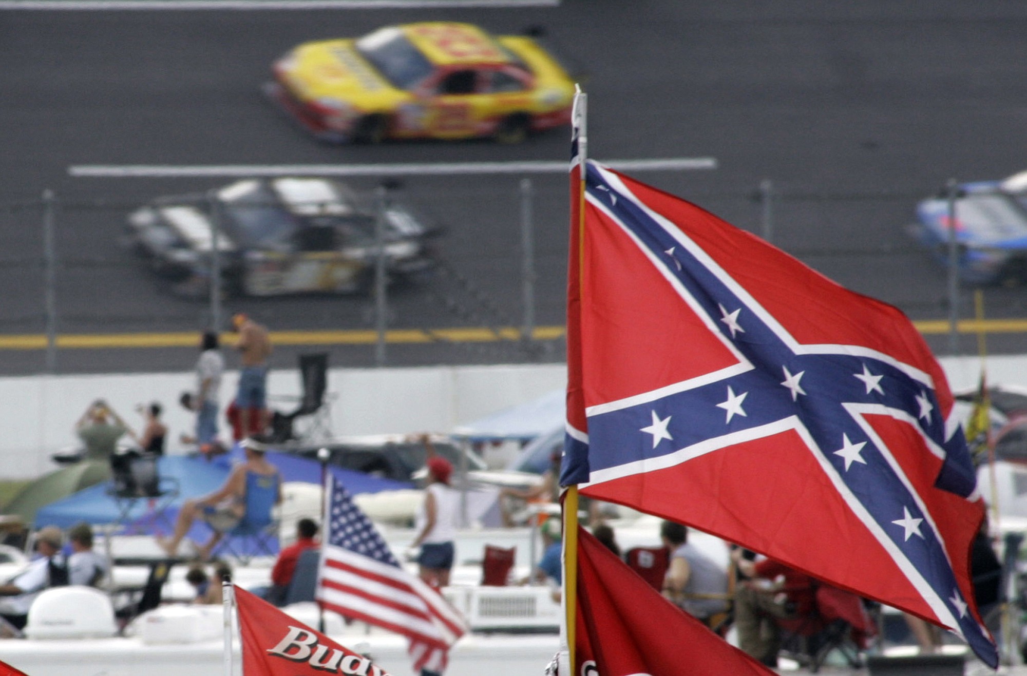A Confederate flag flies in the infield as cars come out of turn one during a NASCAR auto race at Talladega Superspeedway in Talladega, Ala. Though NASCAR bars the use of the flag in any official capacity, many fans fly the flag at their races.