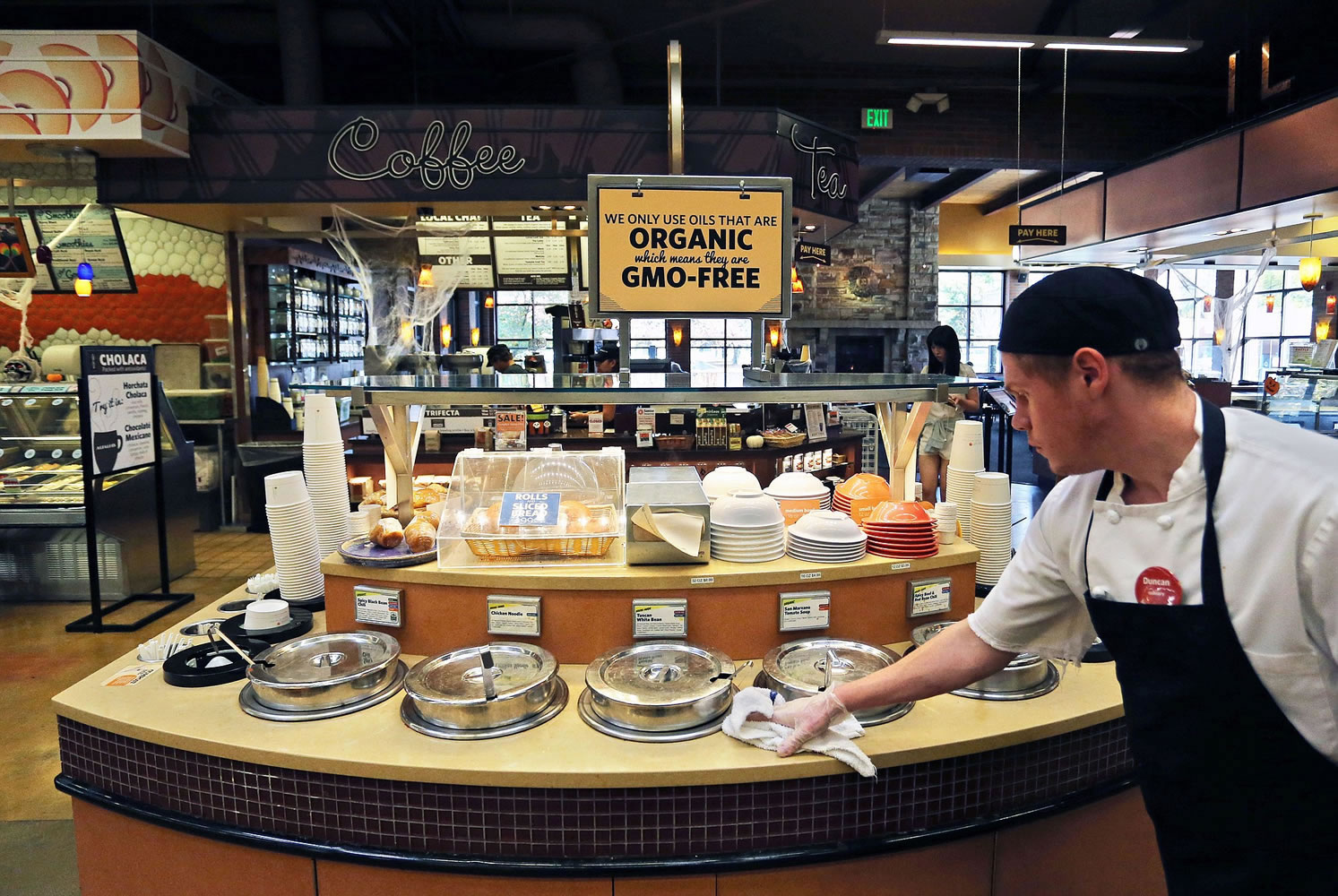 A grocery store employee wipes down a soup bar with a display informing customers of organic, GMO-free oils in Boulder, Colo.